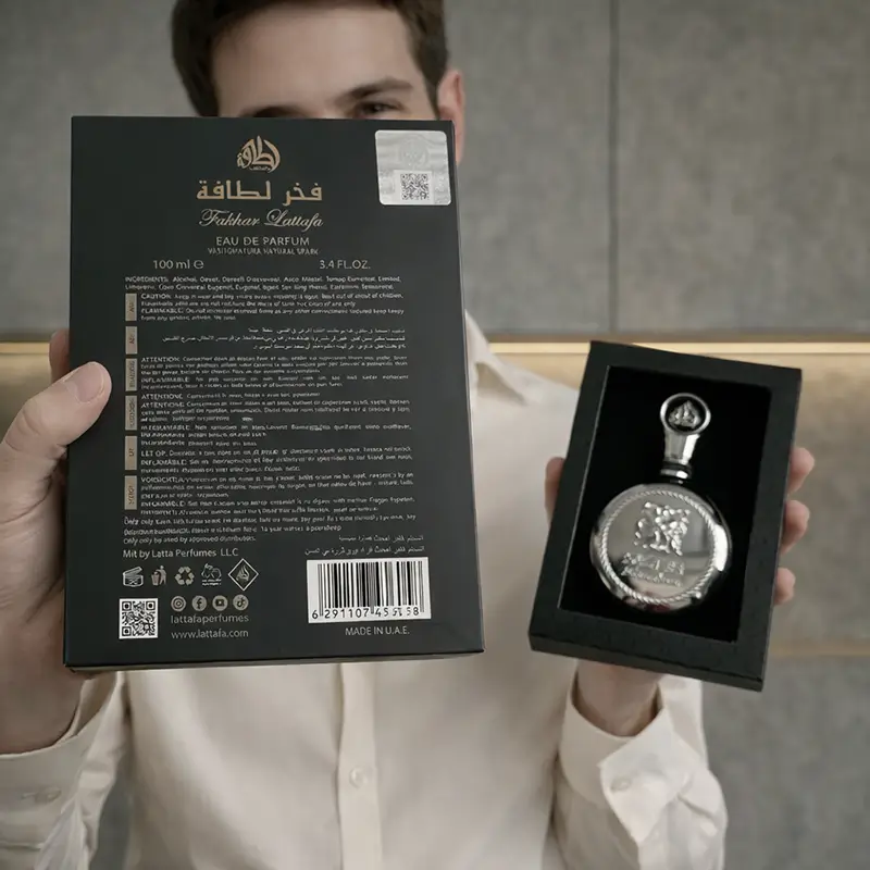 Man holding Lattafa Fakhar Eau de Parfum box and bottle during unboxing display
